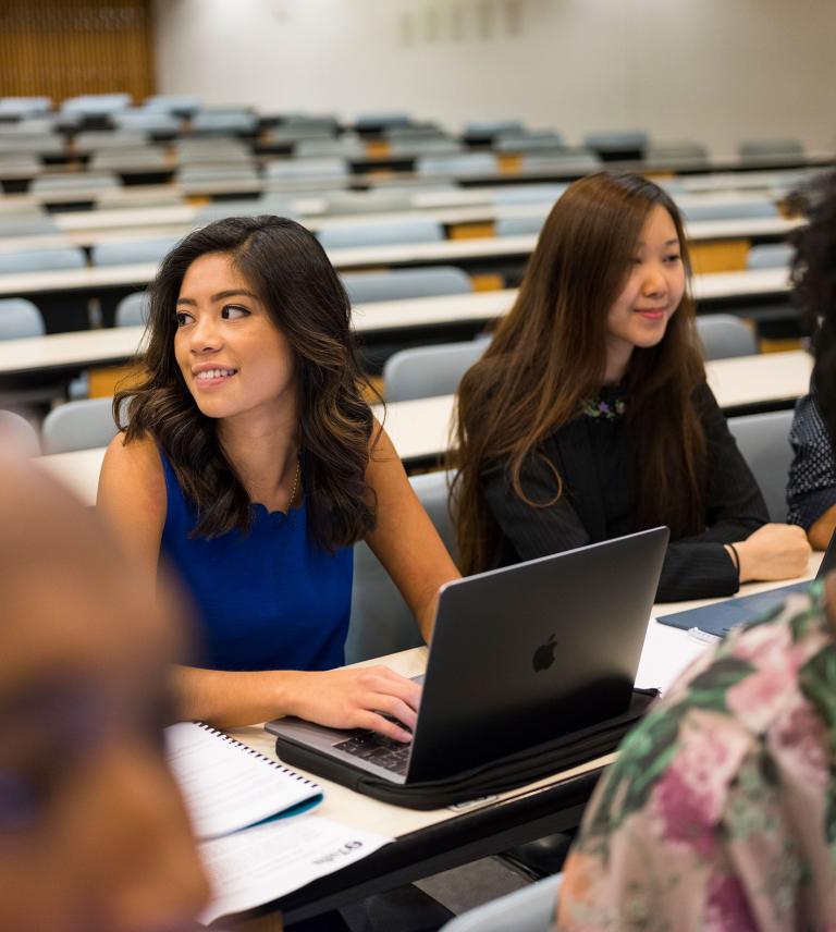 Students sitting in a lecture hall with their laptops