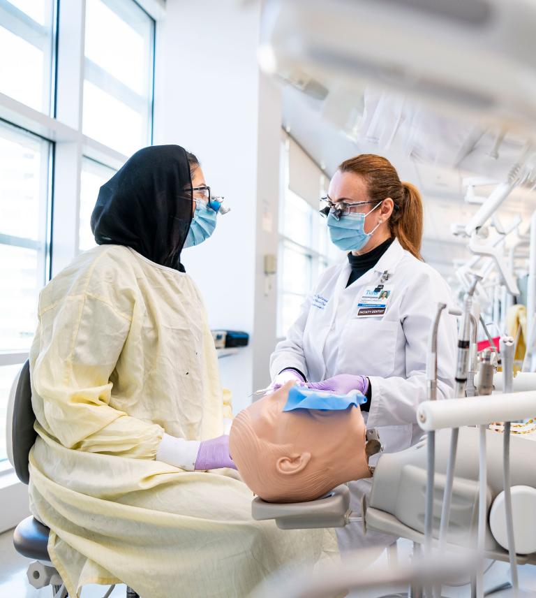 A student and faculty member speak to each other while working in the Simulation Clinic