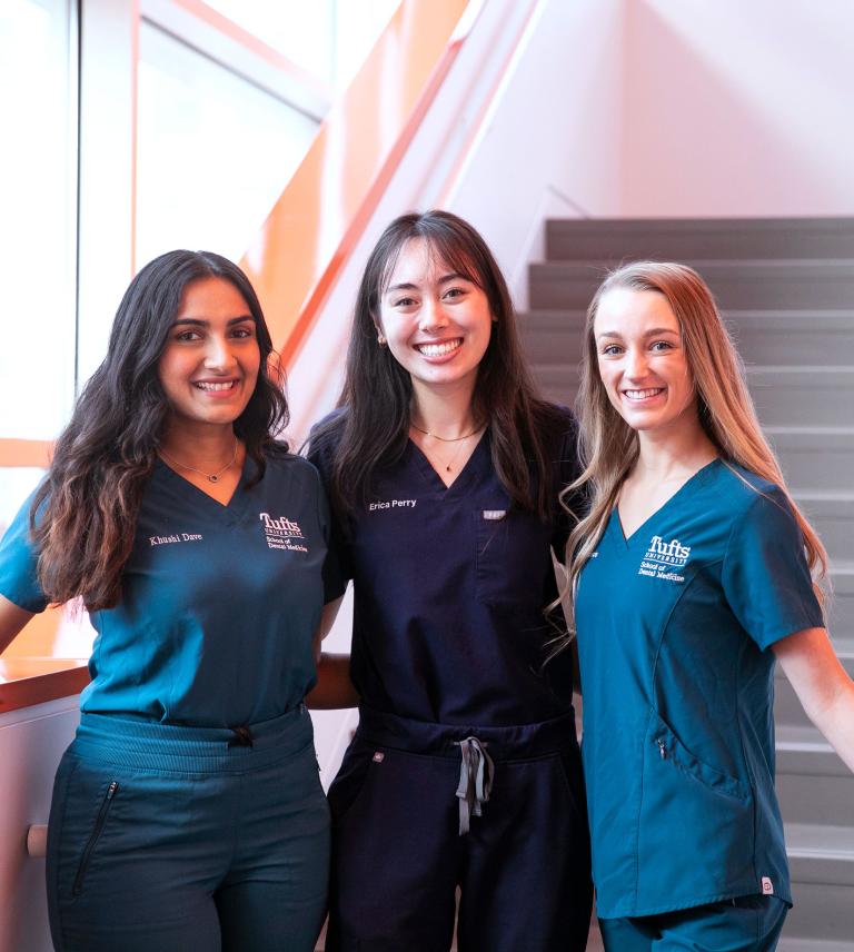 Three smiling students stand together in a stairwell