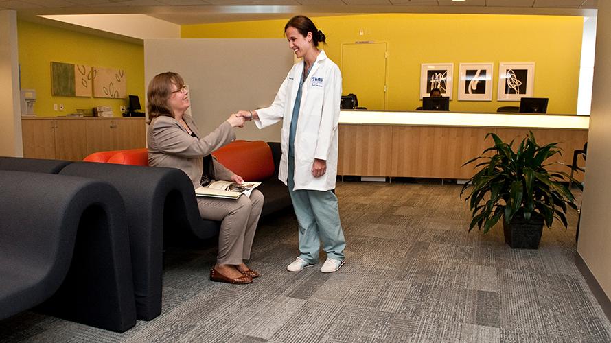 Implant Center staff member shaking hands with patient in waiting room area.
