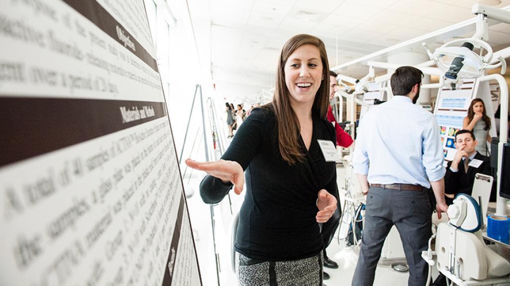 Master's student pointing at poster board