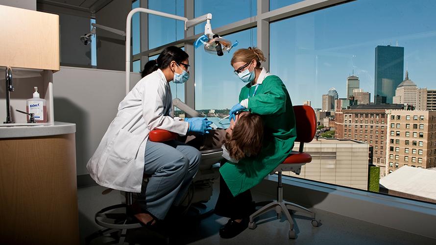 A patient receiving treatment in the dental school with a view of Boston in background