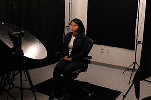 Three video camcorders are positioned to record a seated person