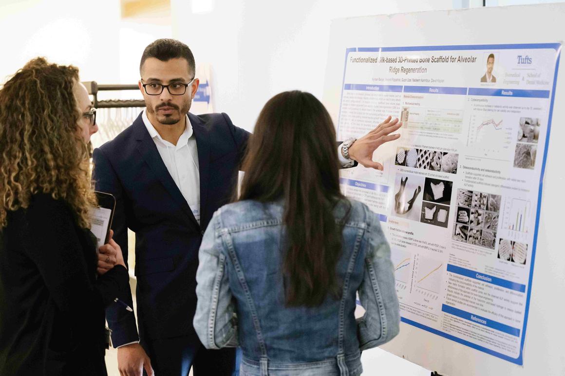 Three people standing at poster board on an easel