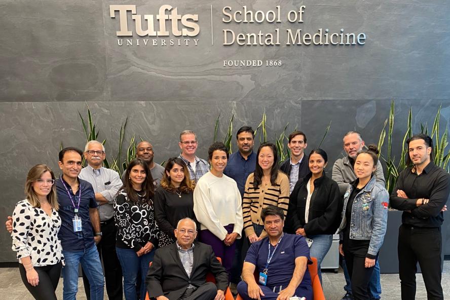 A group of people posing in front of a Tufts University sign that reads "School of Dental Medicine"