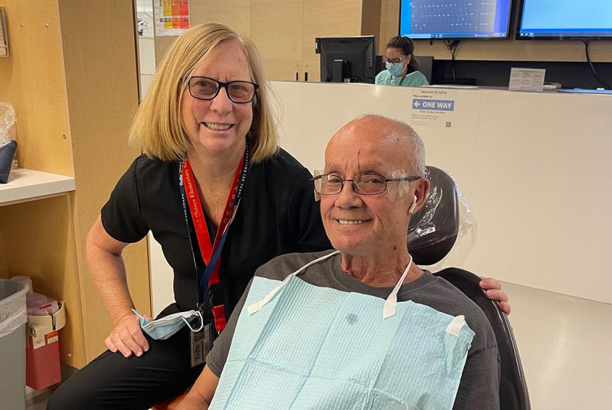 A female dentist and a male veteran patient sitting on the chair, both smiling