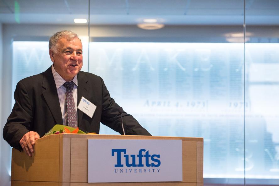 Leonard Carapezza speaking on a podium with the Tufts University Logo