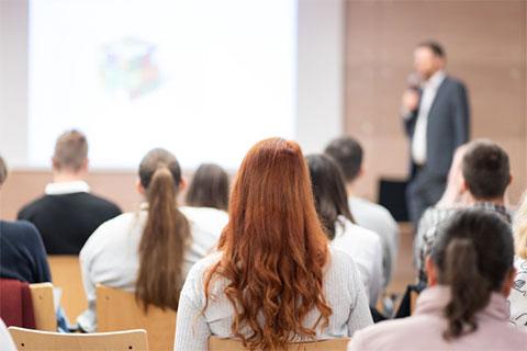 Woman in audience listening to man at microphone