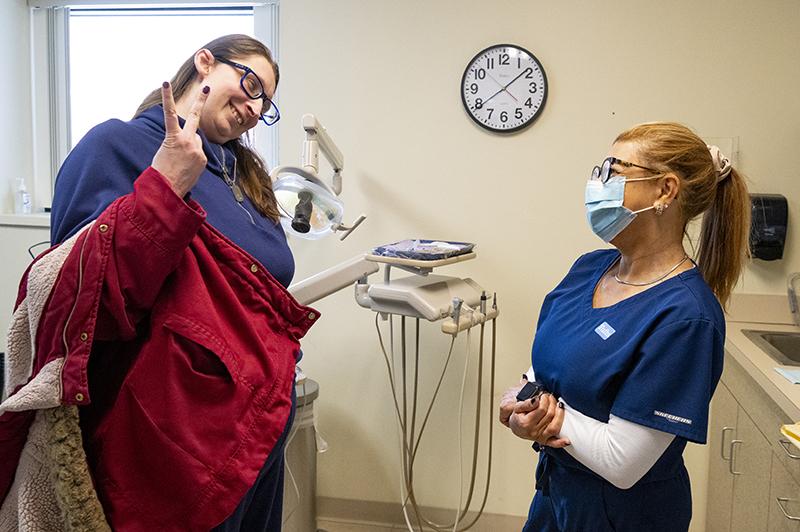 Smiling patient shows two fingers to dental staff