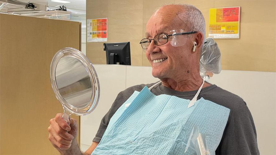 Veteran patient Mr. Stephens smiles, looking at a mirror from the patient chair