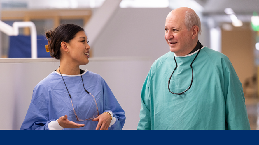 Resident orthodontist and supervising faculty in gowns walk down clinic hallway