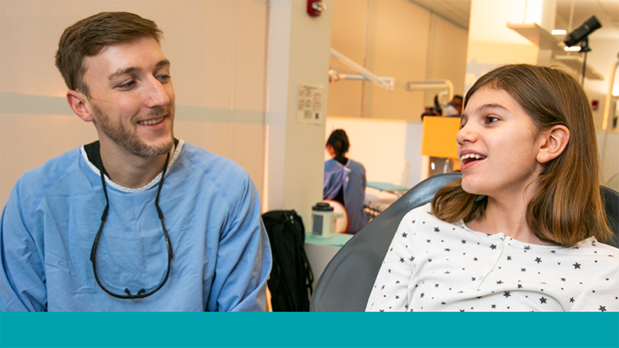 Resident orthodontist smiles at young girl with braces in chair