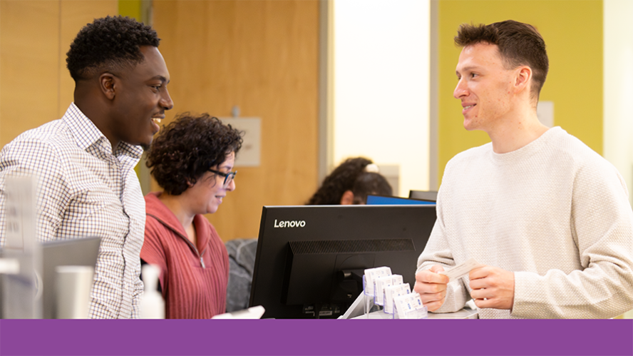 Patient Care Coordinator talks to patient at front desk near computer