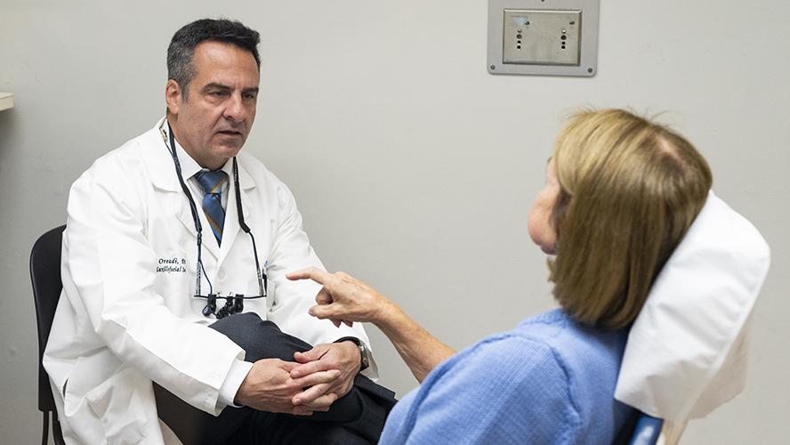 Dr. Daniel Oreadi talks to patient in chair.