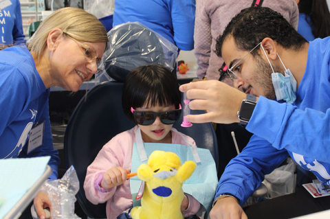 Child in dentist chair plays with stuffed animal