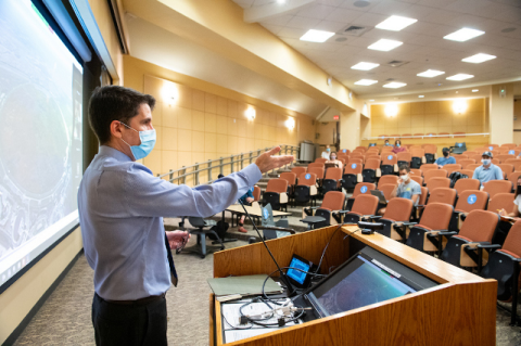 A man with a mask teaching a class from a lectern with students widely spaced out in large room. As COVID-19 changed the world, Tufts pivoted quickly in 2020 to keep students learning and everyone safe