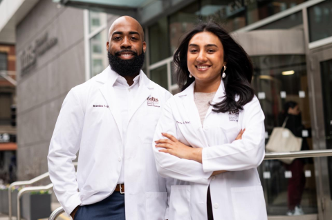 Two dental students wearing their white coats outside Tufts University School of Dental Medicine.