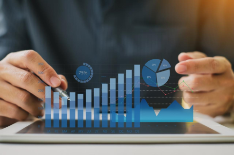 Hands next to a set of bar graphs and pie charts.