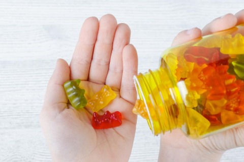 one hand pouring several gummie vitamins into another open hand.