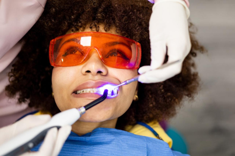 A woman wearing orange-tinted safety classes during dental treatment