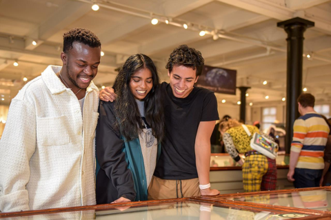 Three young adults look at a museum display case.