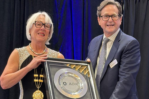 Pamela C. Yelick in evening gown accepts award from IADR CEO in business suit
